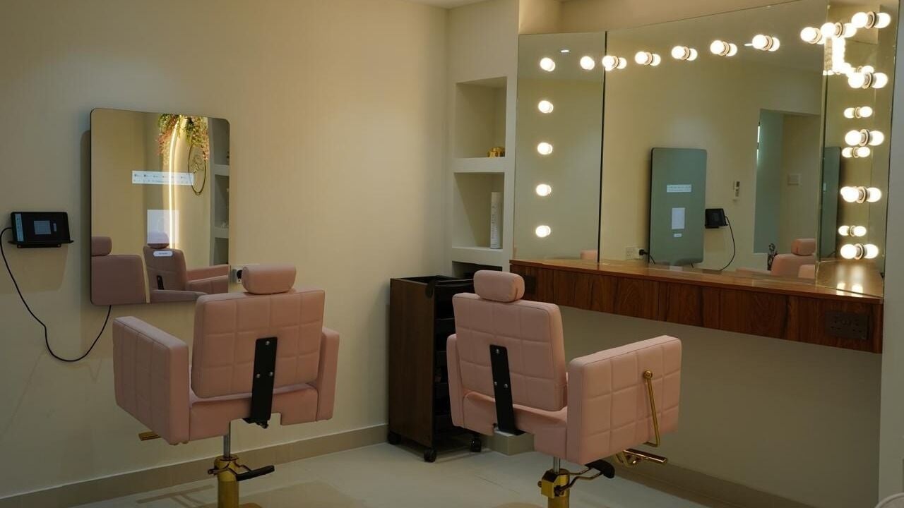 Styling stations with blush-pink chairs and Hollywood mirror